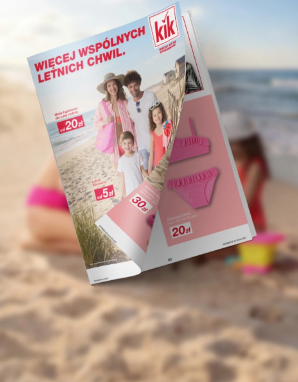 Mama i dziecko spędzają czas na plaży w letniej odzieży kąpielowej – obok widoczna gazetka z sezonowymi ofertami