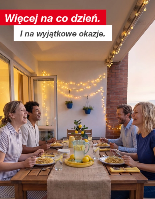 Cztery osoby spędzają wieczorny posiłek, jedząc makaron i pijąc lemoniadę na udekorowanym balkonie z girlandami świetlnymi i roślinami w doniczkach.