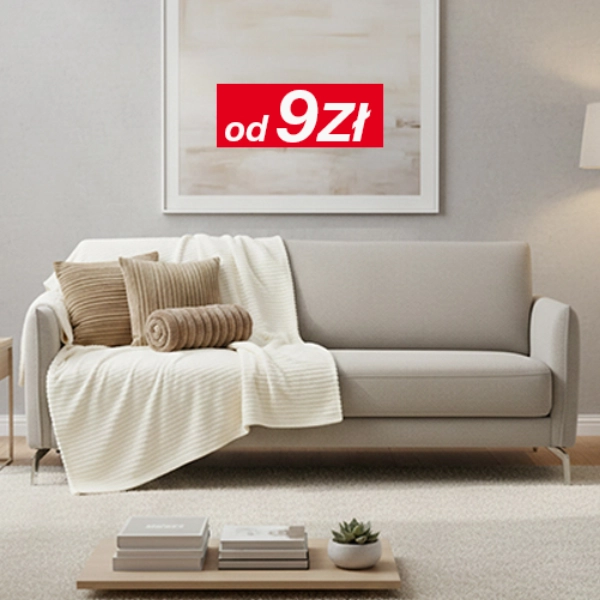 Jasny salon z szarą sofą, poduszkami i kocem, stolikiem i lampą stojącą.
