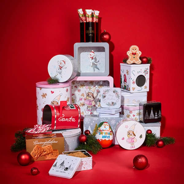 Świąteczna ekspozycja pięknie zdobionych puszek i pudełek na prezenty w różnych kształtach, na tle intensywnie czerwonego tła. W zestawie znajdują się również ozdoby świąteczne.