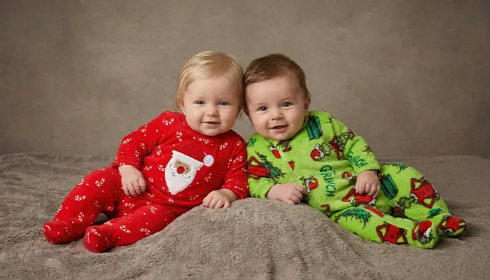 Dwoje niemowląt w kolorowych pajacykach leży obok siebie na kocu. Dwoje niemowląt w kolorowych pajacykach leży obok siebie na kocu.