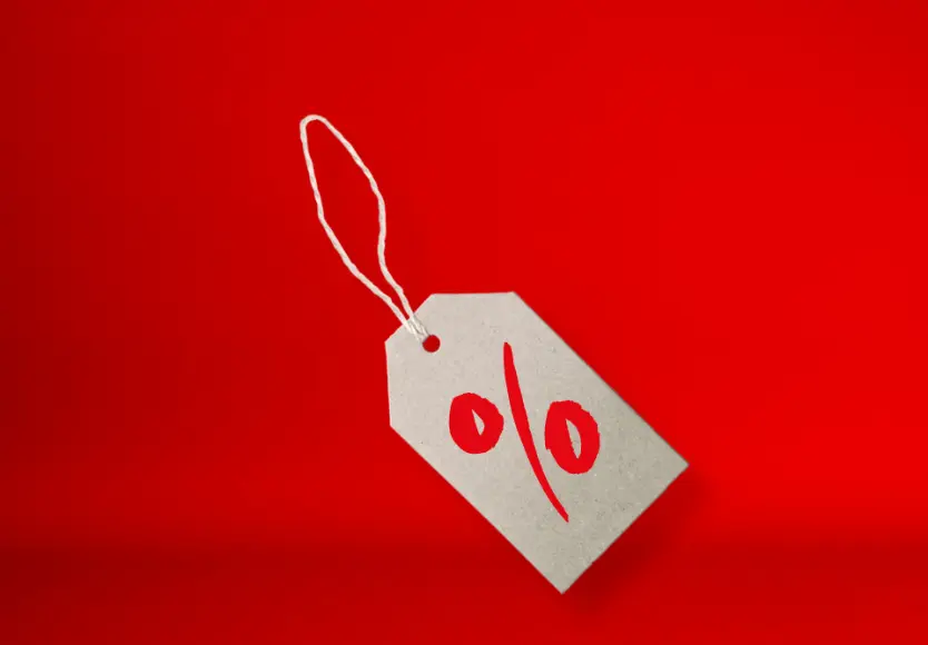 Szara metka cenowa z czerwonym symbolem procenta na jaskrawoczerwonym tle, symbolizująca zniżki lub promocje. Szara metka cenowa z czerwonym symbolem procenta na jaskrawoczerwonym tle, symbolizująca zniżki lub promocje.