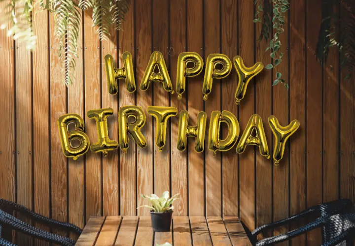 Złote balony z napisem „Happy Birthday” na tle drewnianej ściany.