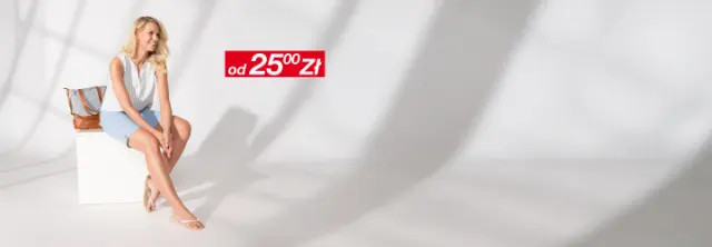 Kobieta ma na sobie lekką, letnią bluzkę i dżinsowe szorty, uśmiecha się radośnie.