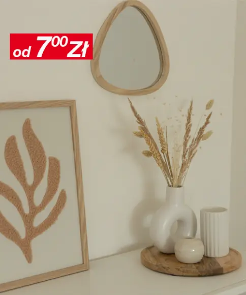 Minimalistyczny wystrój wnętrza, w którym znajduje się małe lustro, oprawiona grafika przedstawiająca liść oraz wazon z suszonymi kwiatami na drewnianej tacy, na tle neutralnej ściany.