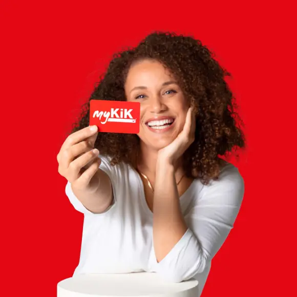 Osoba z kręconymi włosami trzyma czerwoną kartę myKik na czerwonym tle.