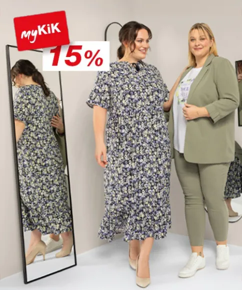 Dwie kobiety stoją przed lustrem i prezentują stylowe stroje, obok tabliczka informująca o 15% rabacie od myKiK.