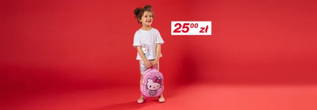 Dziecko stoi przed czerwonym tłem, ubrane w koszulkę w paski z Hello Kitty i szorty, trzymając różowy plecak z Hello Kitty.