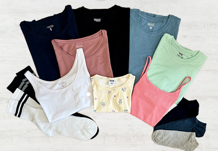 Ujęcie z góry różnych kolorowych topów i skarpetek, w tym koszulek na ramiączkach i T-shirtów w odcieniach niebieskiego, różowego, zielonego, białego i żółtego.