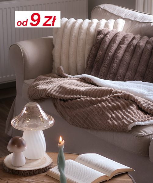 Przytulny salon z miękkimi poduszkami, pluszowymi kocami, świecącą świecą i lampą w kształcie grzyba na drewnianym stole.