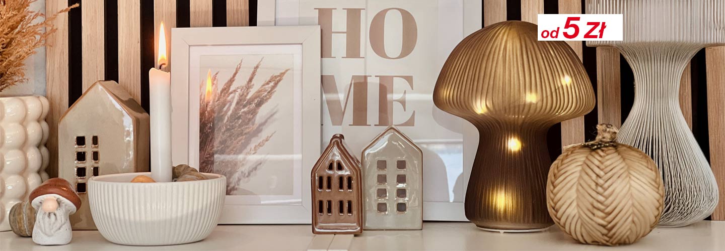 Przytulna ekspozycja elementów dekoracyjnych, w tym świec, ceramicznych domków i stylowych lamp na drewnianym tle, z zaznaczonymi cenami.